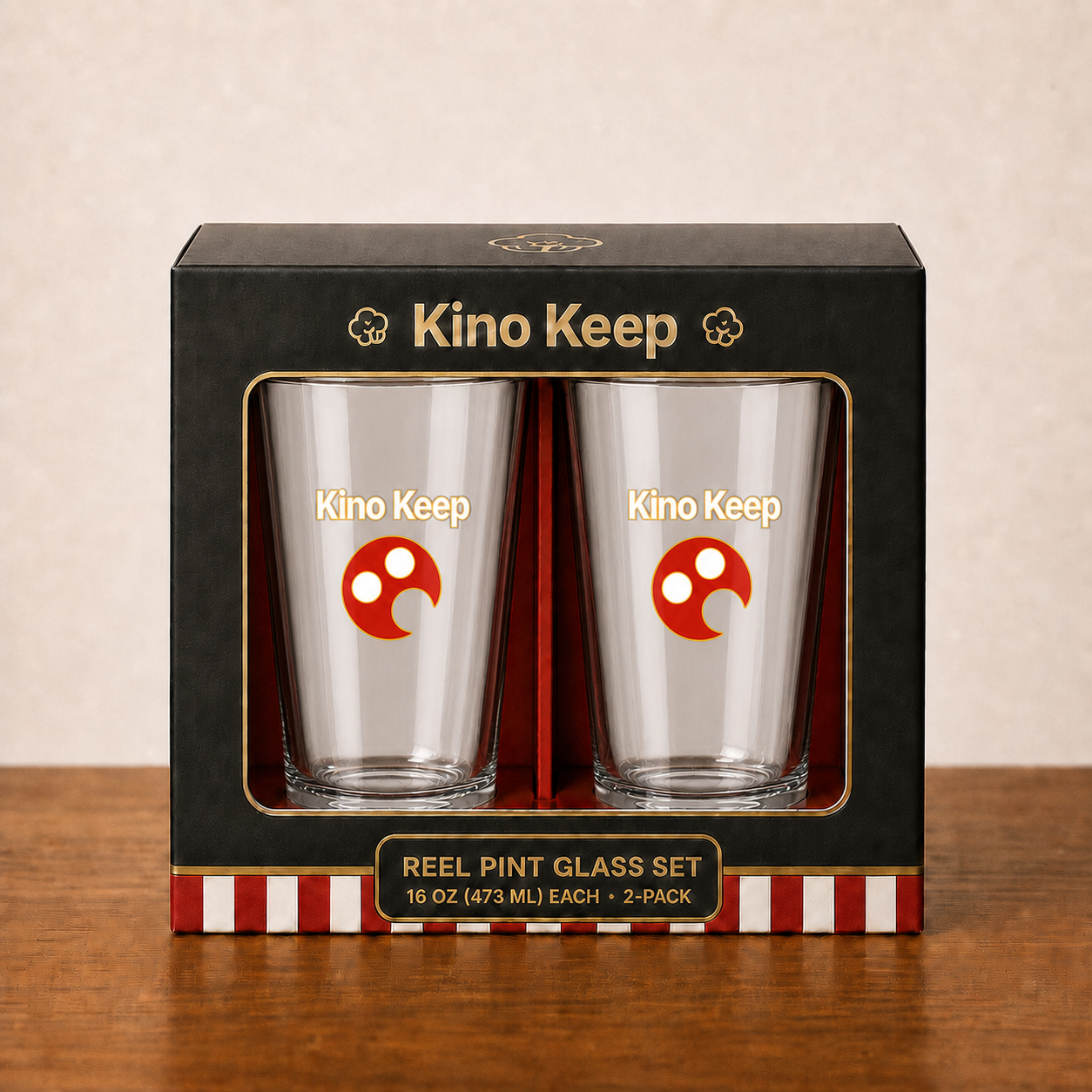 Two clear Kino Keep reel pint glasses in premium black-and-gold retail packaging